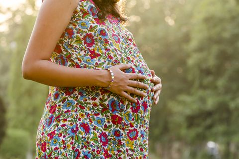 31. SSW: Schwangere im geblümten Kleid hält sich den Bauch