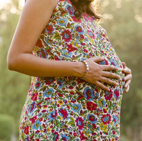 31. SSW: Schwangere im geblümten Kleid hält sich den Bauch