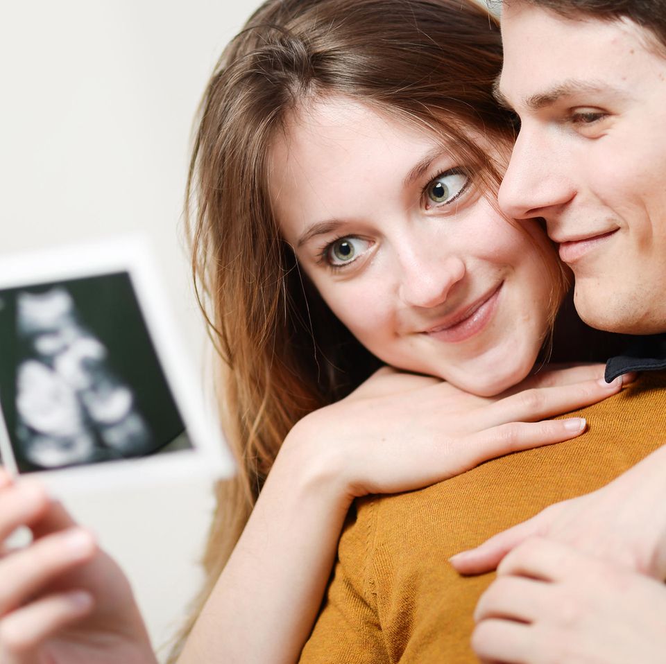 Paar schaut sich Ultraschallbilder glücklich an.