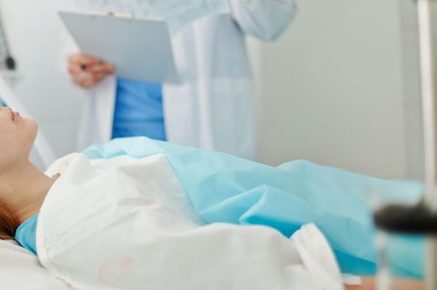 Berlin: Eine Frau liegt im Koma in einem Krankenhausbett, neben ihr steht ein Arzt