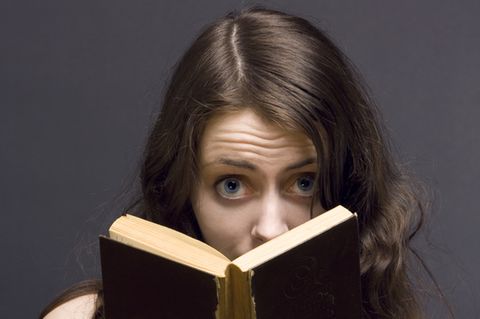 Junge Frau liest aus einem Krimi-Buch