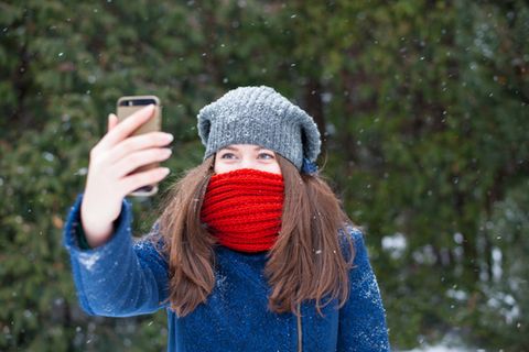 Smartphones bei Kälte: Junge Frau macht ein Selfie im Schnee