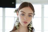 Brautfrisuren: Braut trägt einen Mittelscheitel, zurückgebundene Haare und Blumen im Haar