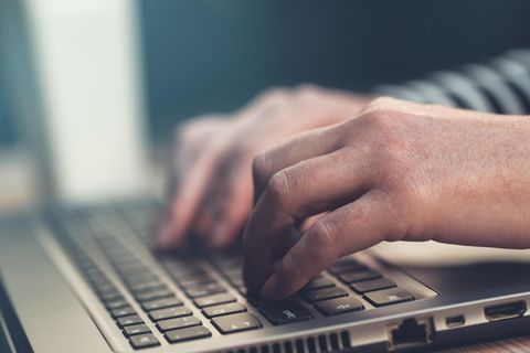 England: Männerhände tippen etwas auf einem Laptop
