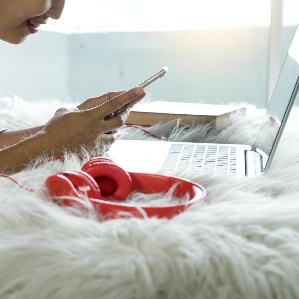 Diese Gewohnheiten machen dumm: Frau mit Smartphone und Laptop im Bett