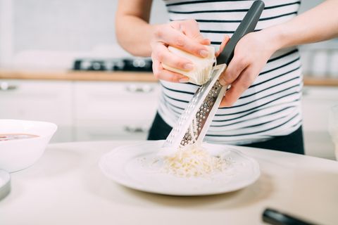 Parmesan in der Schwangerschaft: Schwangere Frau reibt Parmesankäse in Teller