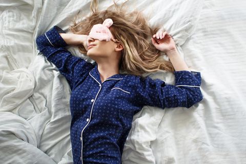 Why you shouldn't sleep on the right side: woman with pajamas and sleeping mask lies in bed