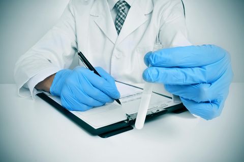USA: Ein Arzt füllt ein Formular aus und hat ein Reagenzglas in der Hand