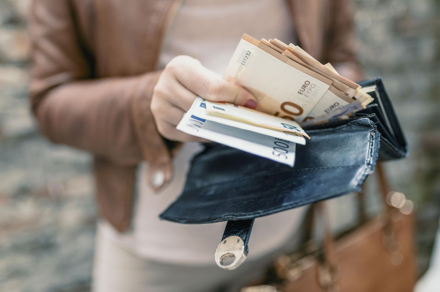 Reich werden: Frau mit Portemonnaie voller Geld