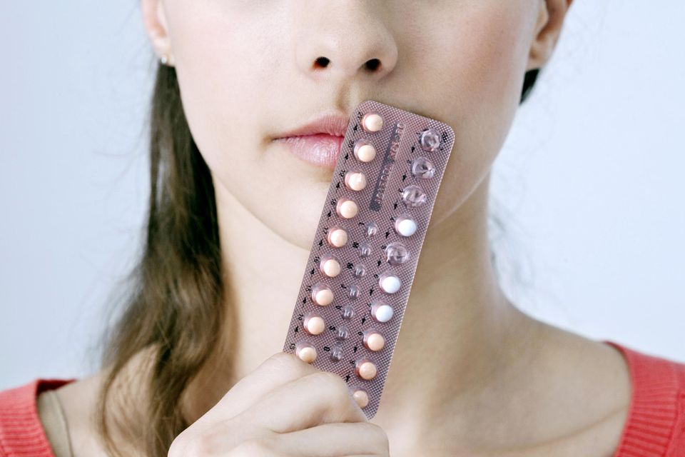 Die Pille für schöne Haut: Frau hält sich eine Packung der Pille vor das Gesicht