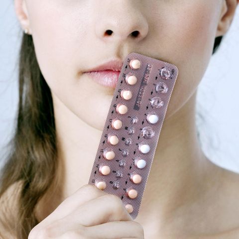 Die Pille für schöne Haut: Frau hält sich eine Packung der Pille vor das Gesicht