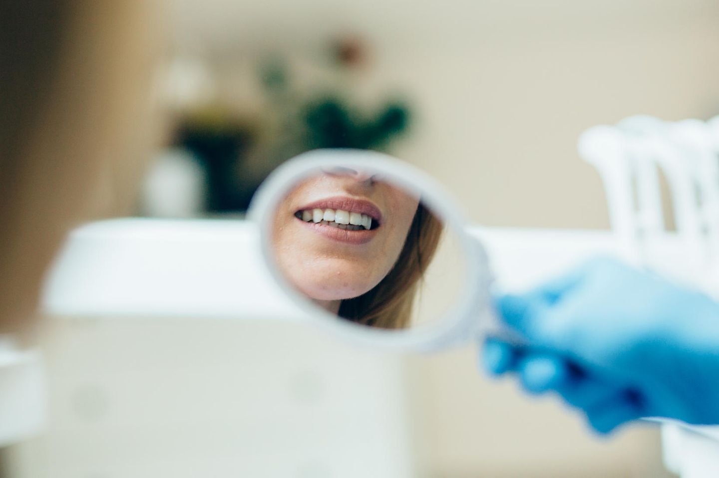 Zahnprobleme Wechseljahre: Frau betrachtet Zähne im Spiegel