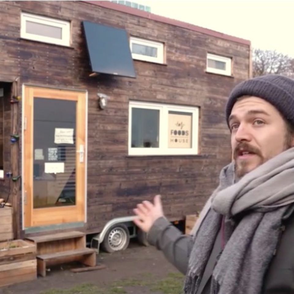 Tiny House für Obdachlose: Mann zeigt auf Haus
