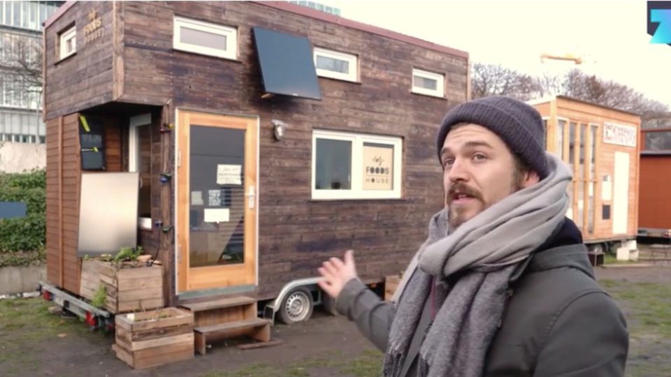 Tiny House für Obdachlose: Mann zeigt auf Haus