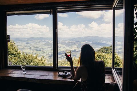 Außergewöhnliche Hotels in Europa: Frau sitzt am Fenster und schaut auf eine Landschaft