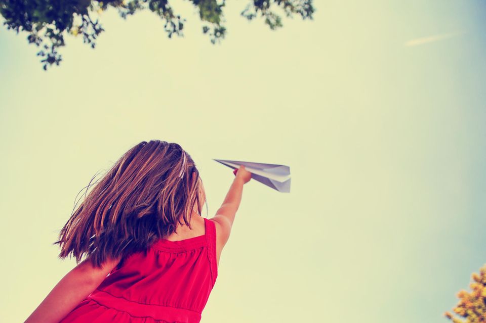 Ein Mädchen spielt mit einem Papierflieger