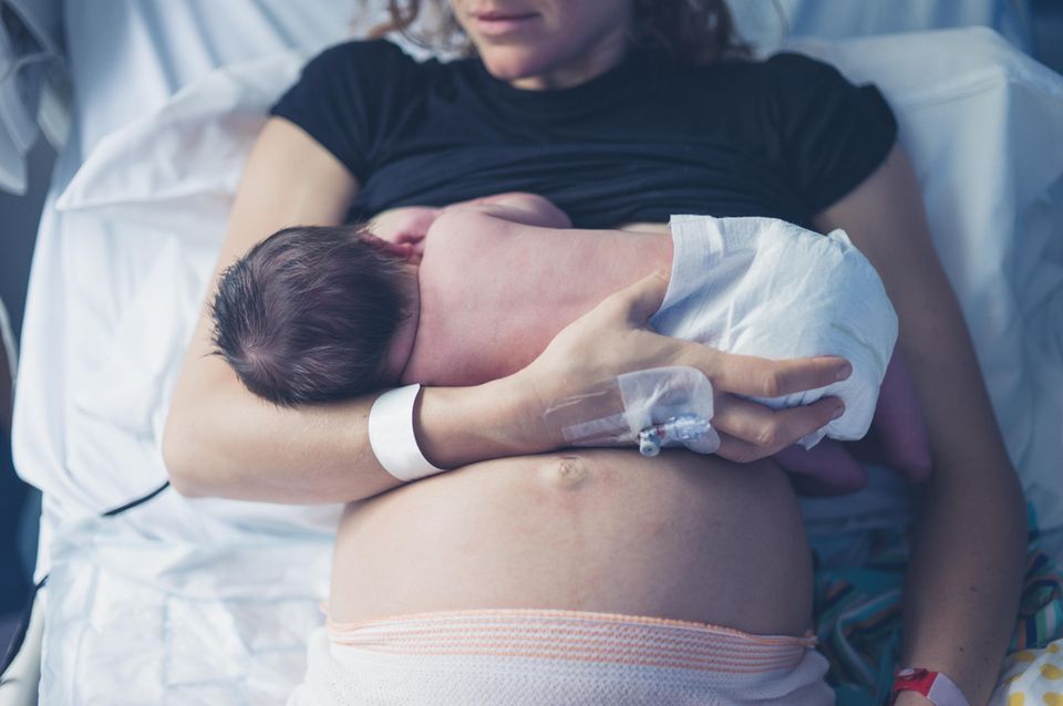 Mutter im Krankenhausbett mit ihrem Baby im Arm