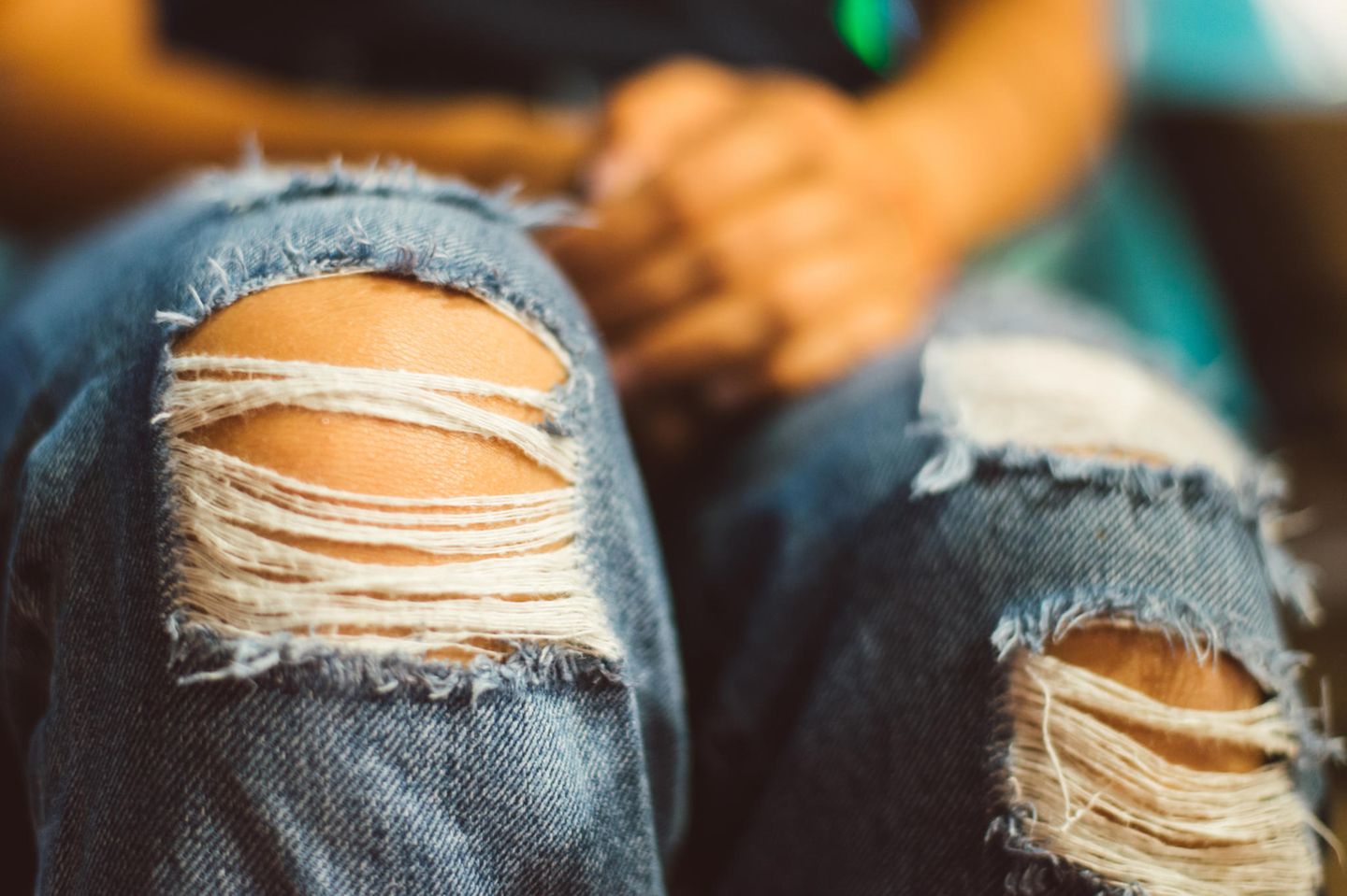Frauenbeine in einer Jeans mit Löchern an den Knien