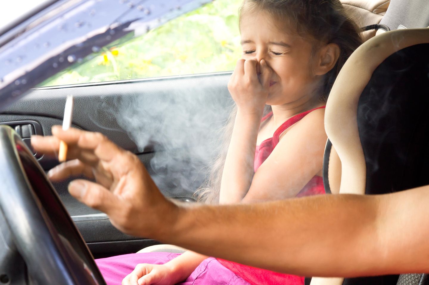 Rauchen im Auto: Frau raucht im Auto mit Kind an Bord