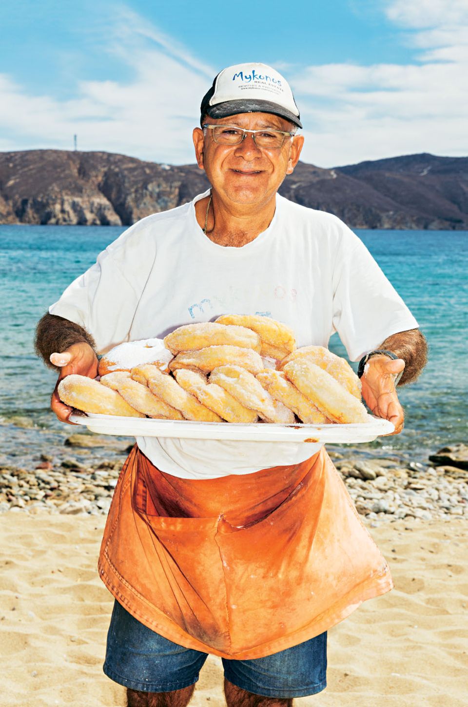 Mykonos Reisetipps: Mann am Strand mit einem Tablett voller Süßwaren
