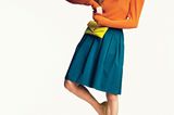 Sommertrends 2018: Model mit orangenem Pullover und blauem Rock