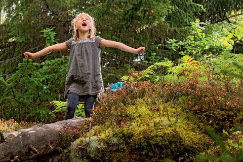 Familienurlaub in Schweden: Mädchen im Wald steht im Regen