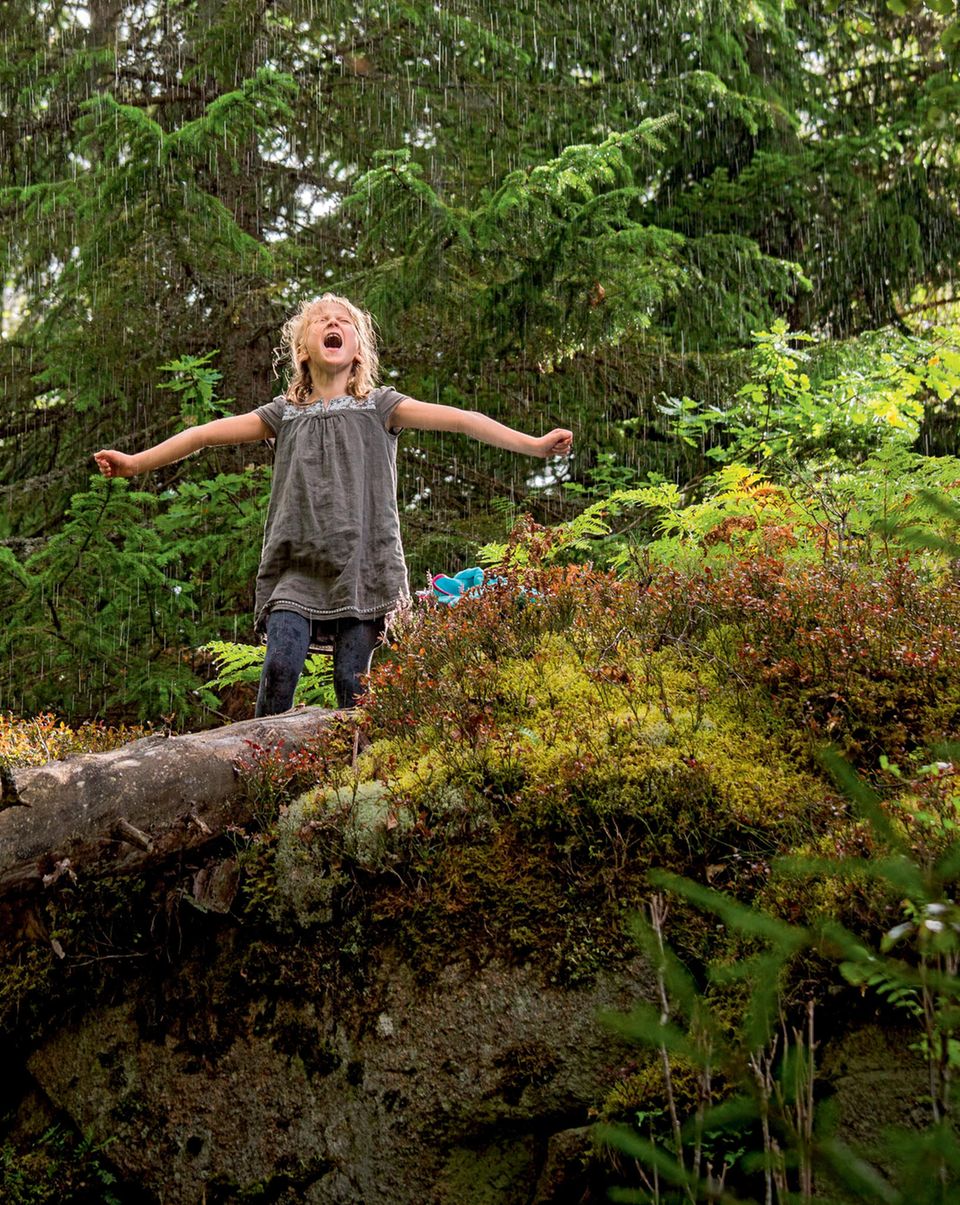 Familienurlaub in Schweden: Mädchen im Wald steht im Regen