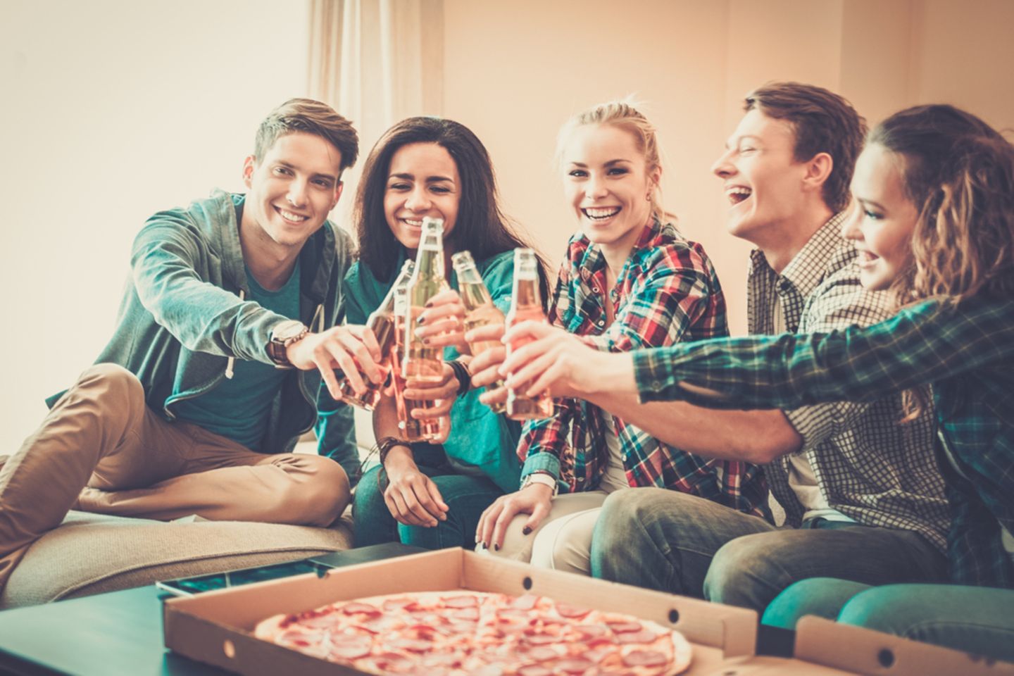 Einweihungsparty: Junge Freunde stoßen an, Pizza und Bier