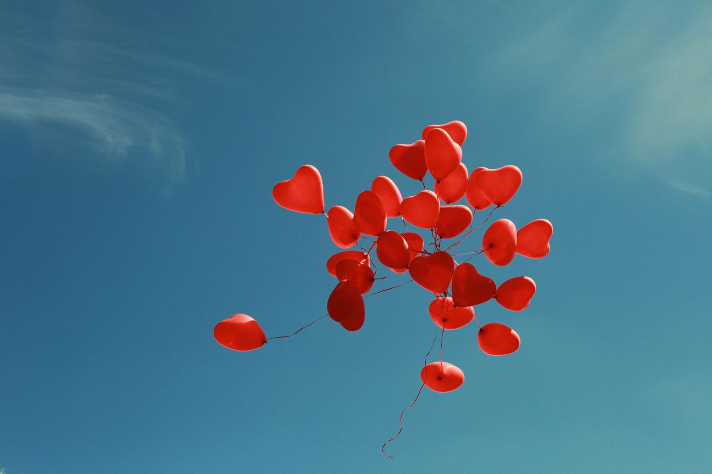 Offene Liebe: Rote Herzchen-Luftballons fliegen in den blauen Himmel
