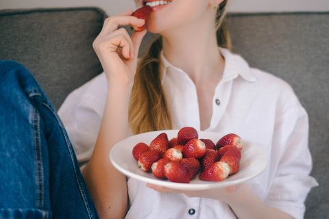 Erdbeerflecken entfernen: Frau isst Erdbeeren