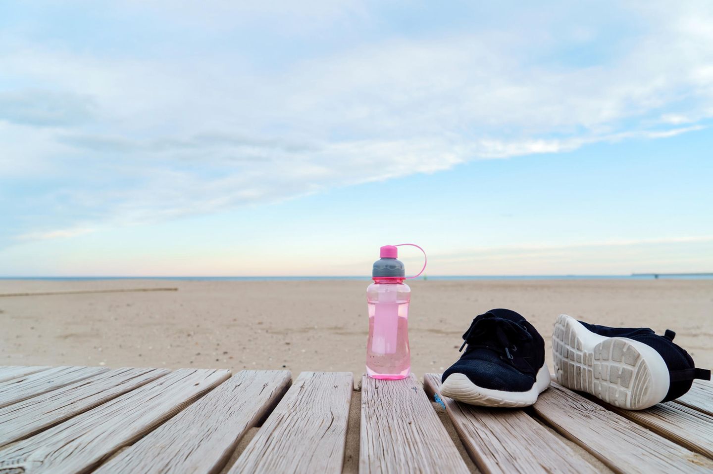Trainingspause: Schuhe und Trinkflasche vor Strand