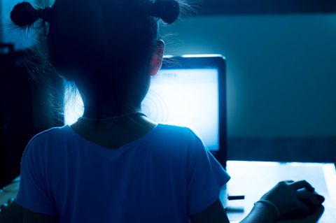 Jugendschutz im Internet: Kind von hinten zu sehen, an einem Laptop sitzend
