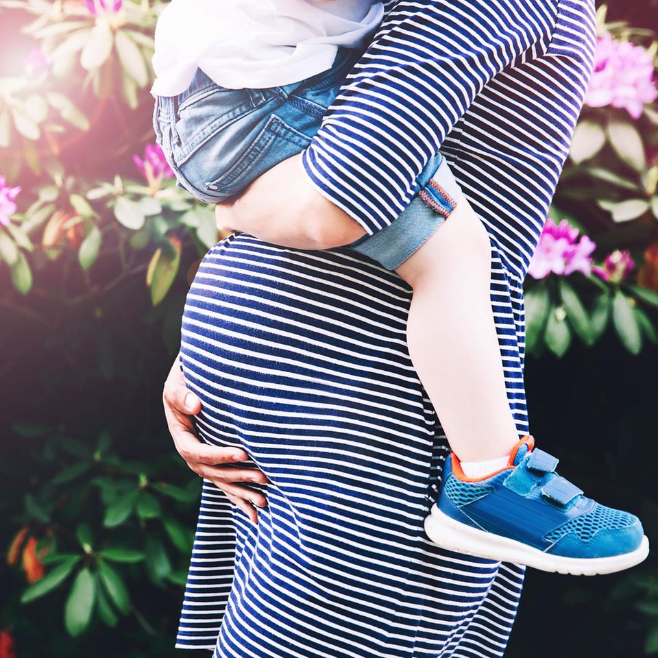 Mutter als Beruf: Eine Schwangere mit einem Kleinkind auf dem Arm