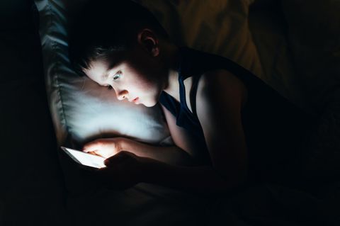 Momo-Challenge: Ein kleiner Junge im Bett mit Smartphone