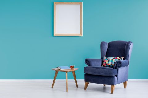 Minimalistisch wohnen: Sessel und Tisch vor fast leerer Wand