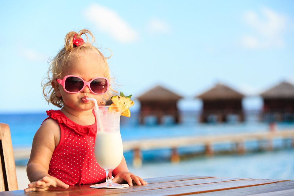 Cluburlaub mit Kindern: Kleines Mädchen schlürft Cocktail am Strand