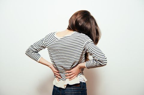 Rückenschmerzen-Ursachen: Frau hält sich den Rücken