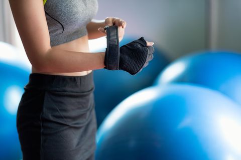 Dieser Trendsport macht dich schlank und fit: Frau zieht Trainingshandschuhe an