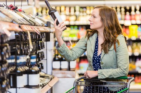 Frau kauft Rotwein in Supermarkt