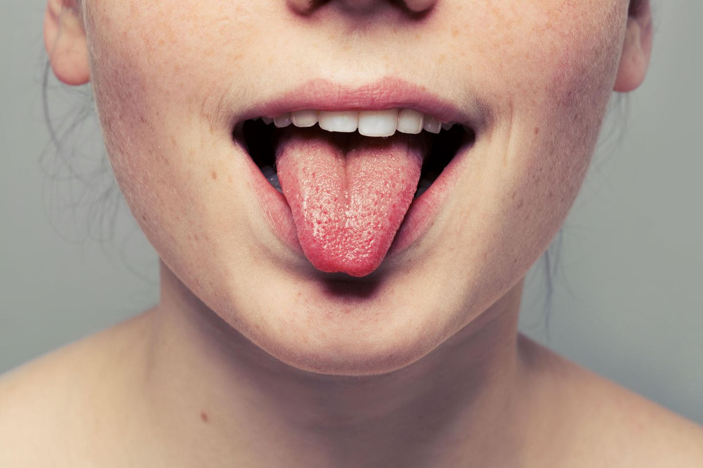 Schwarze, haarige Zunge: Frau streckt Zunge raus