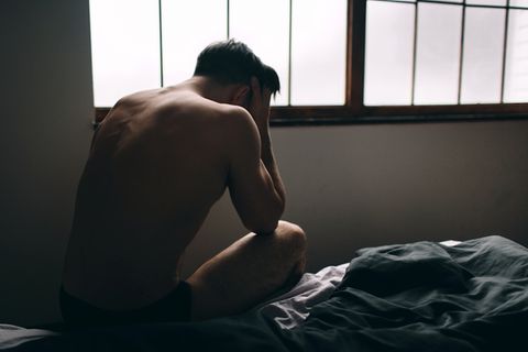 Sexsucht bei Männern: Mann sitzt verzweifelt auf Bett