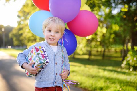 Kindergeburtstagsgeschenke: Kleiner Junge mit Geschenk und Luftballons