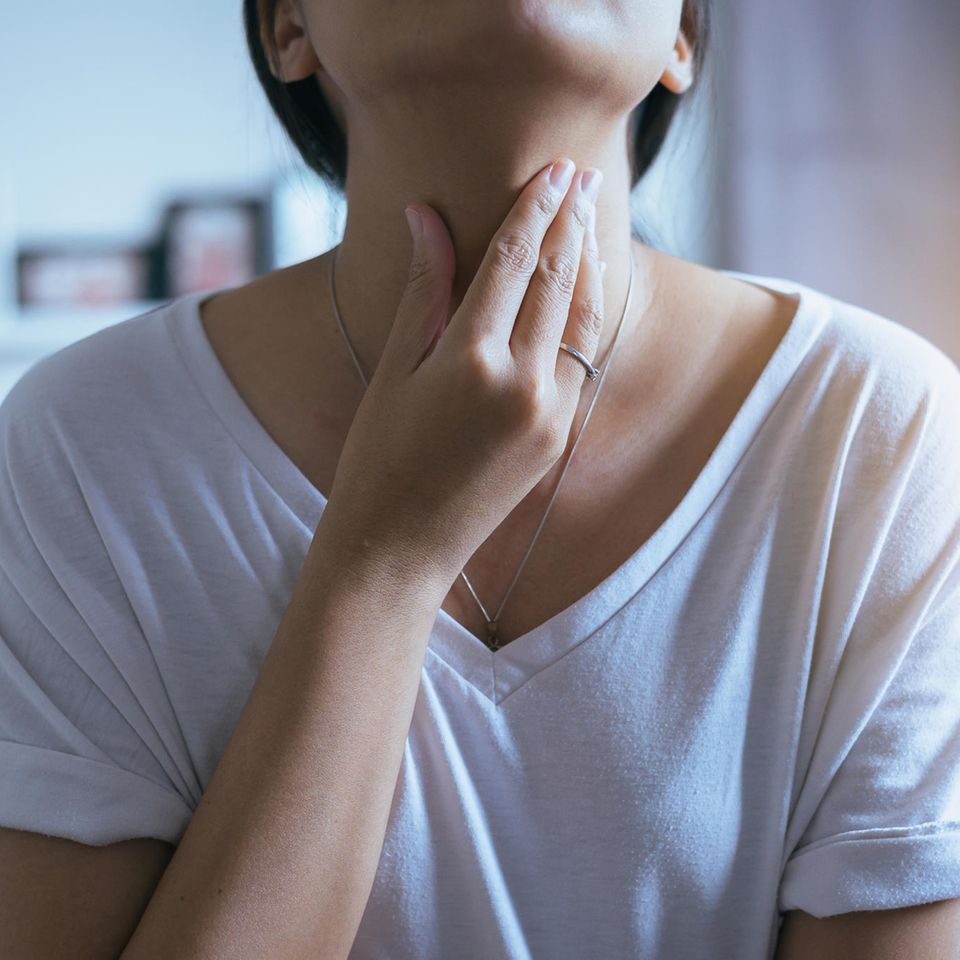 Einseitige Halsschmerzen – Frau fasst sich an den Hals