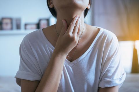 Einseitige Halsschmerzen – Frau fasst sich an den Hals