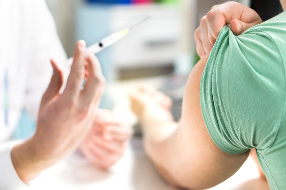 Grippeimpfung: Arzt hält Spitze an den Arm