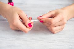 7 Maniküre-Fehler, die jeder schon mal gemacht hat Maniküre-Fehler: Pinker Nagellack wird mit Wattestäbchen ausgebessert