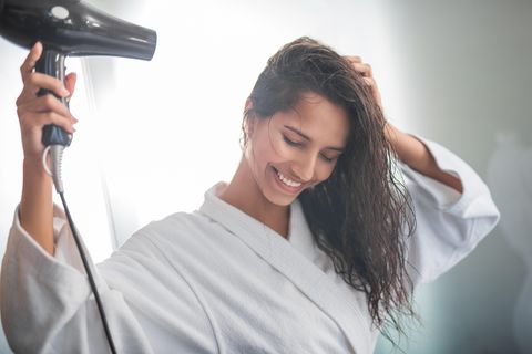 Kalt föhnen: Frau föhnt sich die Haare