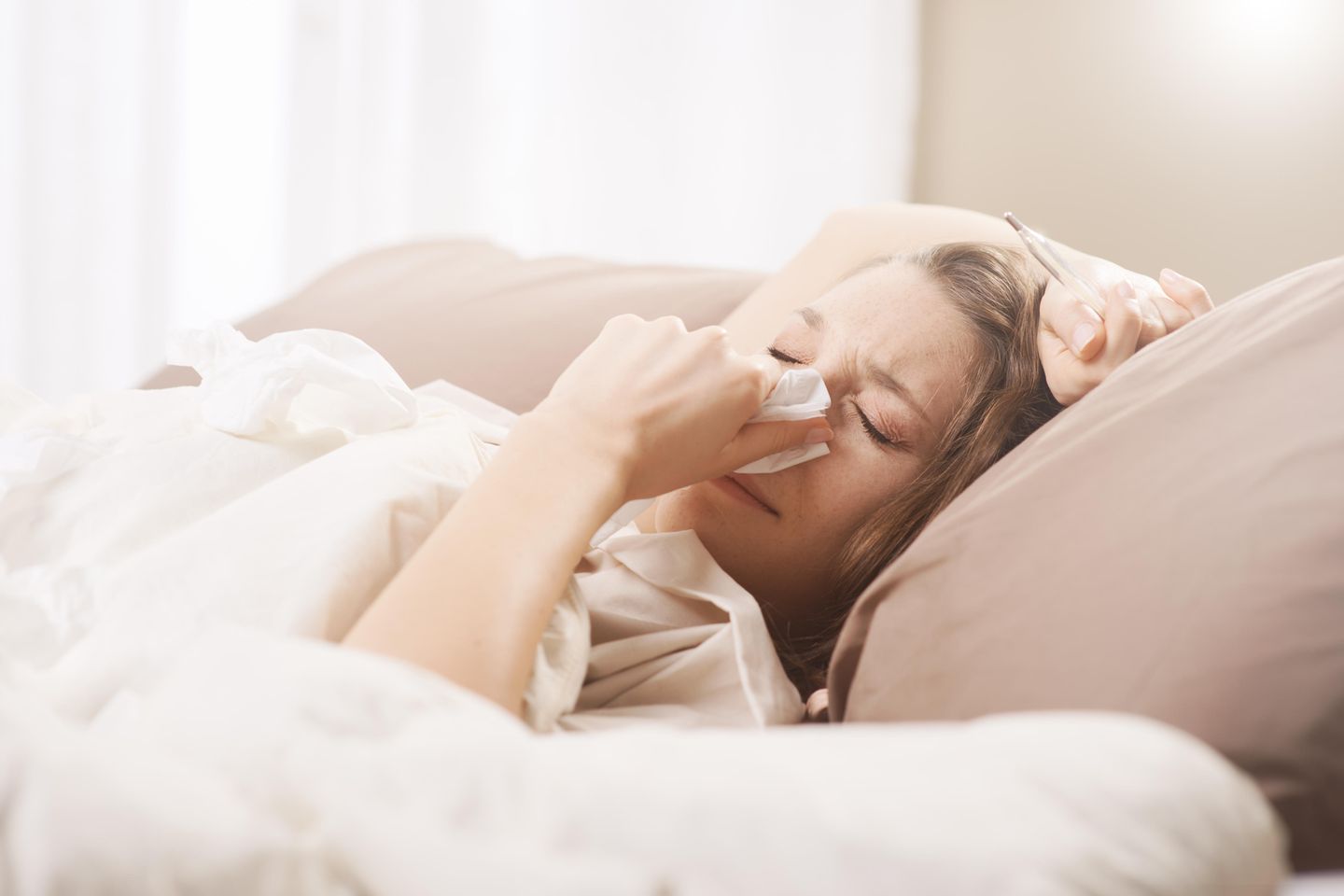 Grippe Dauer: Frau liegt krank im Bett