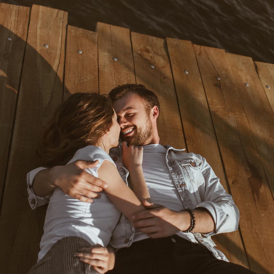 Wahre Liebe: Ein junger Mann hält die Hände seiner Frau mit beiden Händen und küsst sie liebevoll