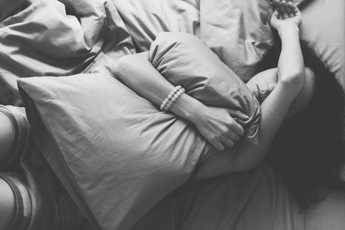 Premenstruelle Dysphorie: Frau verzweifelt auf Bett mit Kissen